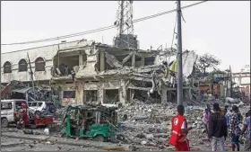  ?? (AP/Farah Abdi Warsameh) ?? People observe a destroyed building and vehicles at the scene of two car bomb attacks Saturday in Mogadishu, Somalia.