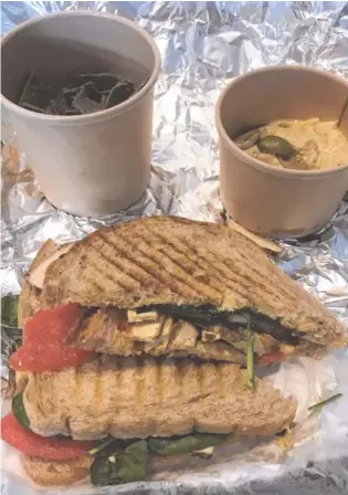  ?? PHOTO BY BARRY COURTER ?? The Toasted Tofu Sandwich features pan-fried tamari tofu, hummus, sun-dried tomato and spinach. I chose as my side hummus with blue corn chips.