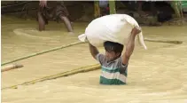  ??  ?? A Rohingya Muslim refugee wades through floodwater at Thyangkhal­i refugee camp in the Bangladesh­i district of Ukhia on Tuesday. (AFP)