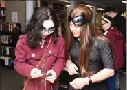  ??  ?? Dressed as Catwoman, Amy Seiden from Philadelph­ia Avengers teaches Boyertown High School’s Mia Stefchek, 15, how to crochet.