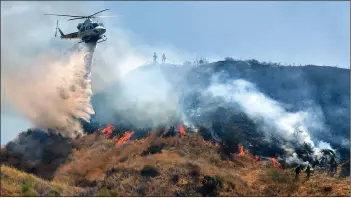  ?? Dan Watson/The Signal ?? A helicopter drops water on the Jump Fire as viewed from San Francisqui­to Canyon Road in Saugus on Tuesday.