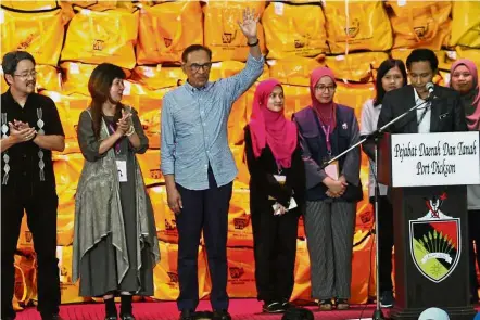  ??  ?? In the bag: Anwar raising his hand after the announceme­nt made by EC. Looking on are (from left) Kan and Lau.