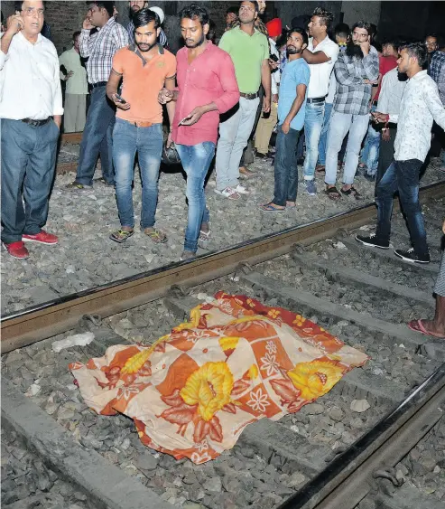  ?? PRABHJOT GILL / THE ASSOCIATED PRESS ?? A cloth covers the body of a victim on a railway track in Amritsar, India, on Friday, after a speeding train plowed through a crowd watching fireworks during a religious festival killing at least 50 people.