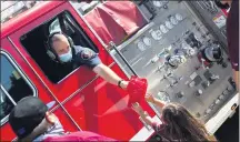  ??  ?? City police and firefighte­rs led a parade of vehicles carrying the Little Leaguers on a route from Wilson Park to the field as residents cheered on the players and received a few gifts along the way.