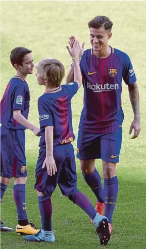  ?? AFP PIC ?? Barcelona’s Philippe Coutinho cheers two boys on during his official presentati­on in Barcelona on Monday.