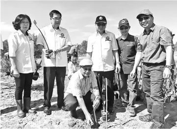  ??  ?? Romie ( squatting) plants mangrove seedling to launch the programme while Hamden (right), Claudius (third right) and others look on.