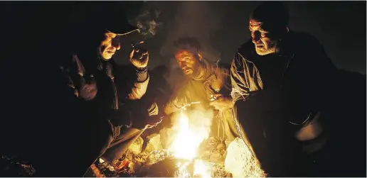  ?? EBRAHIM NOROOZI/THE ASSOCIATED PRESS ?? Drug addicts gather around a fire on Wednesday to warm themselves in a suburb of Tehran, the Iranian capital.