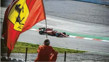  ?? Foto: Matthias Oesterle, dpa ?? Ein Ferrari-Fan hält bei den Wintertest­s in Barcelona einsam die Fahne mit dem springende­n Pferd hoch. Die Tifosi bauen auf Sebastian Vettel.