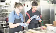  ?? GBA SHIPS E.V./ LINCOLN BACCHUS ?? Jo Bailey (United Kingdom) and Samuel Kunz (Switzerlan­d) prepare lunch for crew members of that Logos Hope in Las Palmas, Spain.