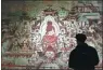  ?? FAN PEISHEN / XINHUA ?? A visitor enjoys a duplicate of Dunhuang frescoes in Lanzhou, Gansu province early this year.