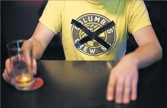  ?? [JOSHUA A. BICKEL/DISPATCH] ?? Justin Fryer of Columbus makes his feelings known about a possible Columbus Crew SC move to Texas via his T-shirt while having a drink at Hendoc’s Pub. The University District bar is a popular hangout for Crew fans.