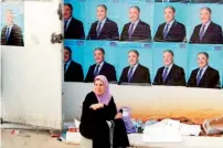  ?? AFP ?? A woman sits in front of posters of Ali Benflis on the last day of the electoral campaign in Algiers. —