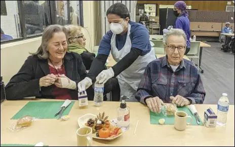  ?? JULIE DRAKE/VALLEY PRESS ?? Volunteer Leslie Gamino (center) gives Amelia Jennings (left) and Ray Homa a carton of milk and bottle of water, Wednesday,
at the Antelope Valley Senior Center, during Los Angeles County Supervisor Kathryn Barger’s Day of Giving event.