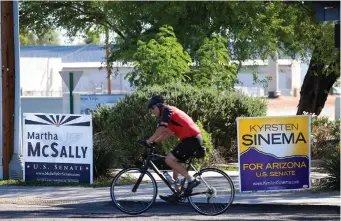  ?? (Reuters) ?? A CYCLIST rides past campaign signs for Arizona US senatorial candidates Kyrsten Sinema and Martha McSally, following the US midterm elections in Scottsdale, Arizona, on November 7.