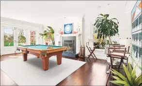  ??  ?? The formal living room, with its high ceiling, cozy fireplace, and bright aesthetic proved the perfect place for a billiards table. The floor plan at 18 Red Top Road provides flexibilit­y for the buyer.