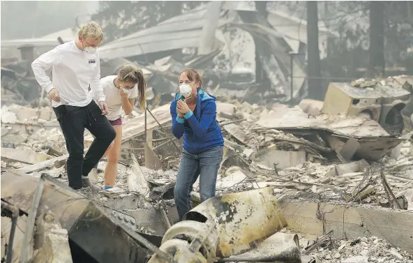  ?? —THE ASSOCIATED PRESS ?? Mary Caughey, right, reacts with her son Harrison, left, after finding her wedding ring in debris at her home destroyed by fires in Kenwood, Calif., Tuesday. Wildfires killed at least 15 people and destroyed more than 2,000 homes and businesses Monday