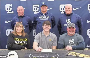  ?? Scott Herpst ?? Angie and Casey Rhudy were among a large crowd on hand at Gordon Lee High School on Friday as their son, Bo, signed his papers to continue his baseball career at Kennesaw State University. Also present for the ceremony were Gordon Lee assistant coaches Thomas Gray and Derek McDaniel and Trojan head coach Mike Dunfee.