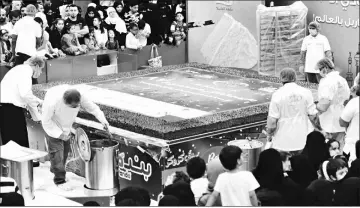  ??  ?? People watch as Saudis assemble a giant marble cake in the city of Jeddah earning them a place in the Guinness World Records for the world’s largest marble cake. — AFP photo