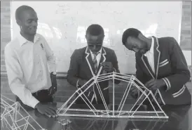  ??  ?? Sizane High School Science Club members, Elton Mawire (centre) and Luther Sibanda work on a bridge after lifting the National Championsh­ips of Bridge Building recently. Following proceeding­s is the Science Club patron, Mr Freedom Gangata