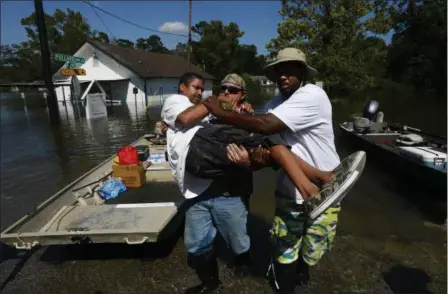  ?? RYAN PELHAM — THE BEAUMONT ENTERPRISE VIA AP ?? Chris McCarty and Mike Taylor help carry Quintin Sanders, who has cerebral palsy, off a rescue boat in the north end of Beaumont, Texas on Thursday. McCarty came from Lufkin, Texas to help rescue people from flooding due to Tropical Storm Harvey.