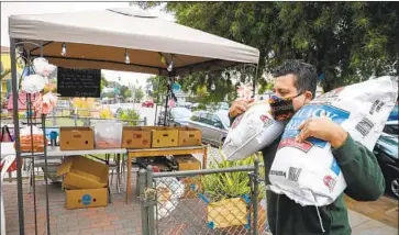  ?? Nancee E. Lewis ?? CHRISTIAN RAMIREZ lugs sacks of beans to supply the Table of Hope and Justice in San Diego. “A lot of the folks that come here are proud, hardworkin­g folks that don’t ever ask for handouts,” he said.