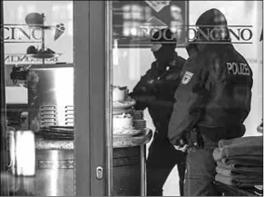  ??  ?? Police stand in an ice cream parlor in Duisberg, in the German state of North Rhine-Westphalia, as raids are carried out against suspected Mafia members. (Photo: CNN Internatio­nal)