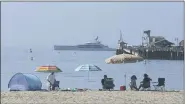  ?? JOHN ANTCZAK — THE ASSOCIATED PRESS ?? Early beachgoers seeking relief from a heat wave secure spots on the shore at Santa Barbara, Calif., on Sunday as the superyacht Bravo Eugenia, owned by Dallas Cowboys owner Jerry Jones, lies offshore.