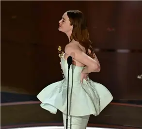  ?? AFP ?? Emma Stone cargaba con una mano su Óscar, mientras con la otra sostenía su vestido. Aseguró que se le dañó poco antes de subir al escenario.