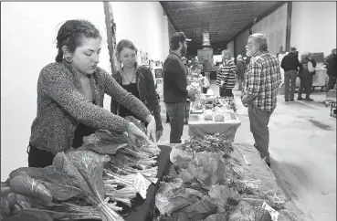  ?? NWA Democrat-Gazette/FLIP PUTTHOFF ?? Emily Jackson (left) and Kayla Lindsey, both with Rocky Comfort Natural Farm in Crosses, arrange produce Saturday at the farm’s booth at the Fayettevil­le Farmers Market. The winter market opened Saturday indoors at Evelyn Hills Shopping Center, 1554 N. College Ave. The winter market is open from 9 a.m. to 1 p.m. each Saturday through March.