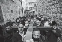  ?? Mahmoud Illean / Associated Press ?? Christians carry a cross along the Via Dolorosa toward the Church of the Holy Sepulchre in Jerusalem’s Old City.