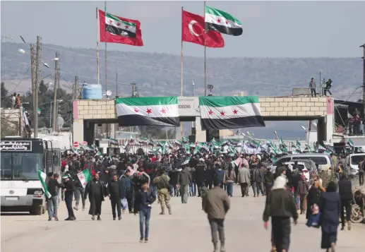  ?? (Khalil Ashawi/Reuters) ?? INTERNALLY DISPLACED Syrians hold Syrian opposition flags during a protest in support of the Turkish army and Turkey-backed Syrian rebels at the Bab el-Salam border crossing between the Syrian town of Azaz and the Turkish town of Kilis earlier this week.