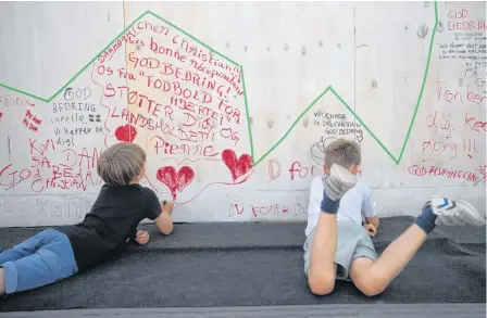  ?? REUTERS ?? People write get-well messages on a wall at a fanzone in Copenhagan on Sunday after Denmark’s Christian Eriksen collapsed on the pitch during his side’s Euro 2020 match with Finland on Saturday.