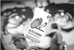  ??  ?? A man in Mexico City holds a placard during a protest with union workers and farmers as NAFTA renegotiat­ion begins inWashingt­on, DC.The placard reads‘FTA hurts, Mexico better without FTA’. — Reuters photo