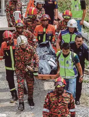  ?? PIX BY HAFIZ SOHAIMI ?? Fire and Rescue Department personnel removing a body from the rubble at the Gombak Putra LRT station in Kuala Lumpur yesterday.
