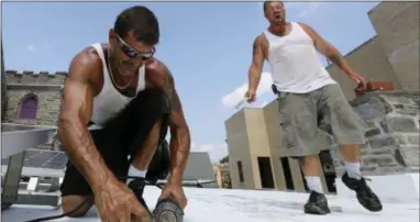  ?? DAVID SWANSON — THE PHILADELPH­IA INQUIRER VIA AP ?? Roofers Ricky Yarnall, left, and Mike Oakes are convinced it is 40 degrees hotter on the top of the Central Baptist Church in Wayne, Pa. as they work through Wednesday afternoon.