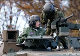  ?? (File Photo/AP/Pool/Kiyoshi Ota) ?? Kishida (left) rides Nov. 27 on a Japan Ground Self-Defense Force Type 10 tank during a review at the JGSDF Camp Asaka in Tokyo.