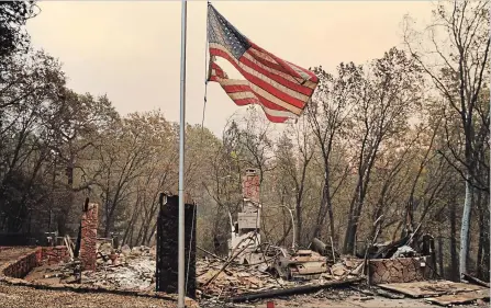  ?? JOHN LOCHER THE ASSOCIATED PRESS ?? A flag flies over a burned home Sunday in Paradise, Calif. Fires continue to burn across the state but some progress was made in containing them.