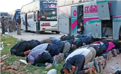  ?? AFP ?? Syrians pray as buses with Jaish Al Islam fighters and their families on board arrive from their former rebel bastion of douma in eastern Ghouta at the Abu Al zindeen checkpoint controlled by Turkish-backed rebel fighters near the Syrian town of Al...