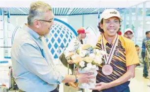  ?? – BERNAMAPIX ?? National Paralympic cyclist Mohamad Yusof Hafizi Shaharuddi­n (right) receives a bouquet of flowers from the National Cycling Federation of Malaysia (PKBM) chairman Abdul Halim Md Yusoff at KLIA.