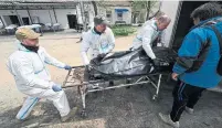  ?? GENYA SAVILOV AFP VIA GETTY IMAGES ?? Mortuary workers unload the body of a victim in Bucha on Thursday, killed during the Russian invasion of Ukraine.