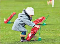  ??  ?? For their tomorrow: a child lays a wreath at the Garden of Remembranc­e in Glasgow