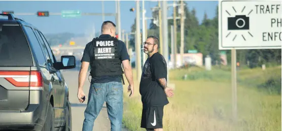  ?? PHOTOS: JURIS GRANEY ?? Shane Daly stands, handcuffed, on the shoulder of Spruce Grove’s Highway 16A on July 25 after being arrested in the first of a series of coordinate­d apprehensi­ons by the Alberta Law Enforcemen­t Response Team. Police say Daly is a full-patch member of the Dirty Few Motorcycle Club and charged him in connection with cocaine traffickin­g.