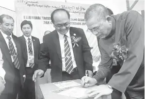  ??  ?? FADILLAH menandatan­gani dokumen sebagai simbolik perasmian Kejohanan Taekwondo ITF Sekolah-Sekolah Sarawak dan Jemputan Kebangsaan 2017 di Kuching semalam sambil disaksikan Master Johnny (tengah) serta tetamu jemputan lain.