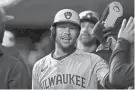  ?? KATIE STRATMAN/USA TODAY SPORTS ?? Brewers outfielder Blake Perkins high-fives teammates in the dugout after scoring on a single by Christian Yelich in the third inning against the Reds on Tuesday night. Perkins had three hits, three RBI and scored twice in the game.