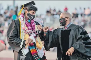  ?? Photograph­s by Robert Gauthier Los Angeles Times ?? NICHOLAS ANDRADE gets a fist-bump from Sierra Vista High Principal Vince Pratt at the Baldwin Park school’s graduation ceremony June 3. The pandemic robbed graduates of many of senior year’s milestones.