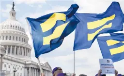  ?? JACQUELYN MARTIN/AP 2017 ?? People hold up “equality flags” near Capitol Hill in support of transgende­r troops. The Pentagon has undone rules enacted in the Trump presidency.