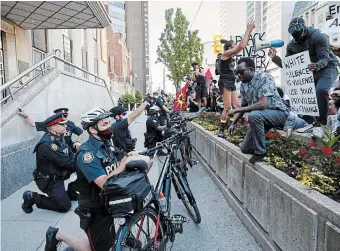  ?? COLE BURSTON GETTY IMAGES ?? Toronto Police officers take a knee outside the United States Consulate during an anti-racism march.