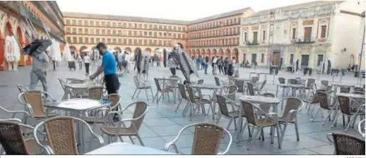  ?? JUAN AYALA ?? Las terrazas de la plaza de la Corredera, en pleno proceso de recogida en el primer día del cierre anticipado de los establecim­ientos.