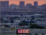  ?? (AP/Matt York) ?? A sign displays an unofficial temperatur­e in July as jets taxi at Sky Harbor Internatio­nal Airport at dusk in Phoenix.