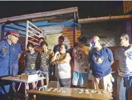  ?? MIGUEL DE GUZMAN ?? Police officers question some of the 12 persons arrested in a drug sting at a house on Mascardo street in Makati City Monday night.